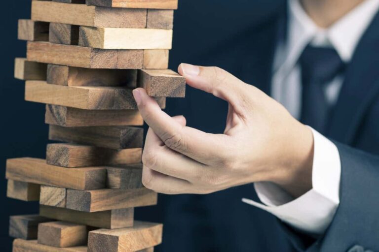 This Is the Dividend Stock I’d Hold Through Market Volatility man in business suit pulls a piece out of wobbly wooden tower